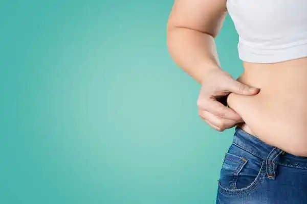 Image of woman pinching her love handles to show weight gain Walton on the Hill