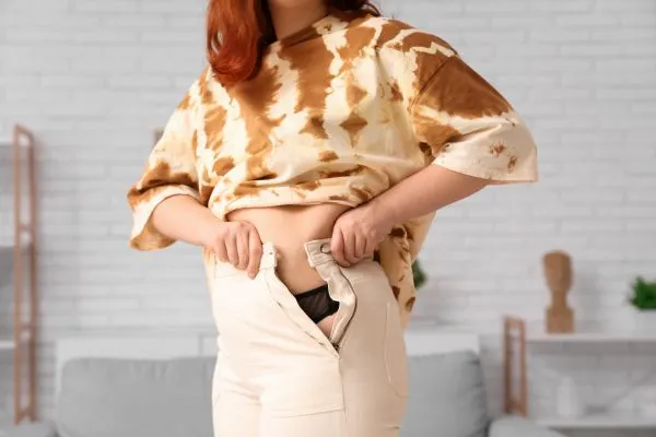 Image of woman trying to do her trousers up after pregnancy weight gain Walton on the Hill