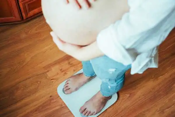 Image of woman weighing herself and experiencing weight gain through pregnancy Walton on the Hill